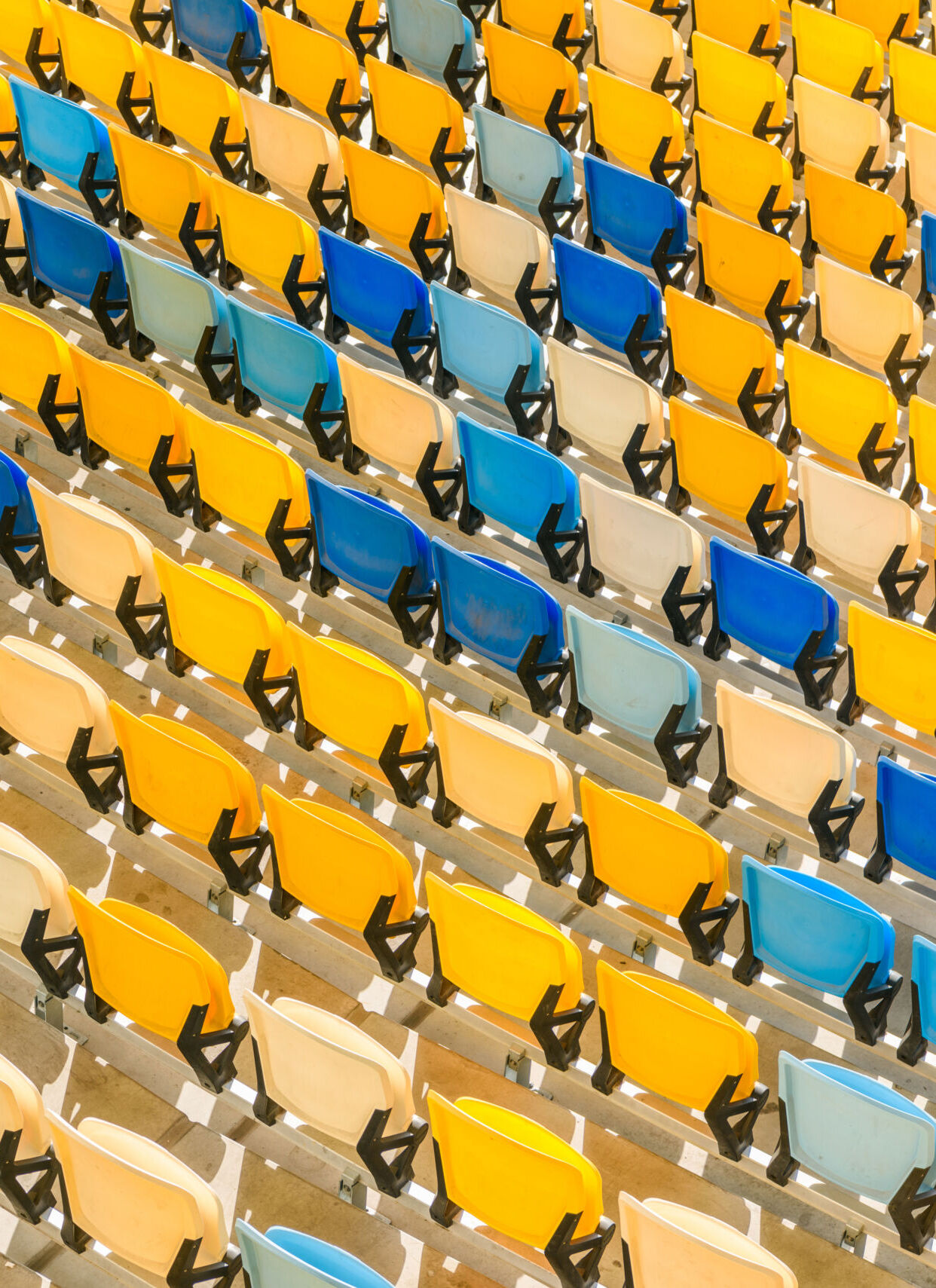 elevated view of rows of yellow and blue stadium seats background